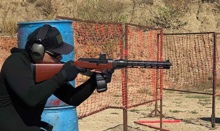 a shooter aiming a Ruger PCC firearm that resembles a Soviet PPSh-41 in a competitive shooting or tactical training scenario. 